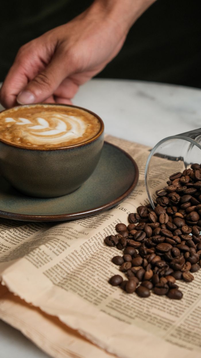 services-01 Handcrafted coffee with latte art, surrounded by coffee beans on a rustic table.
