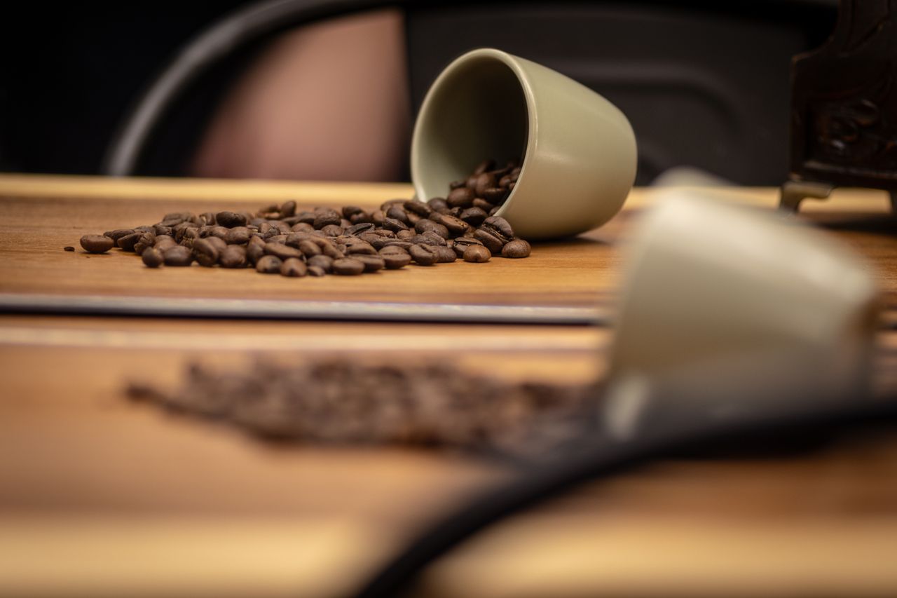 footer-cta Spilled coffee beans from a cup on a wooden surface, creating a cozy and aromatic scene.